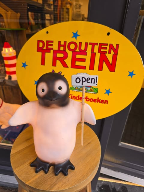 Het logo van De Houten Trein met een vrolijke speelgoedpinguïn